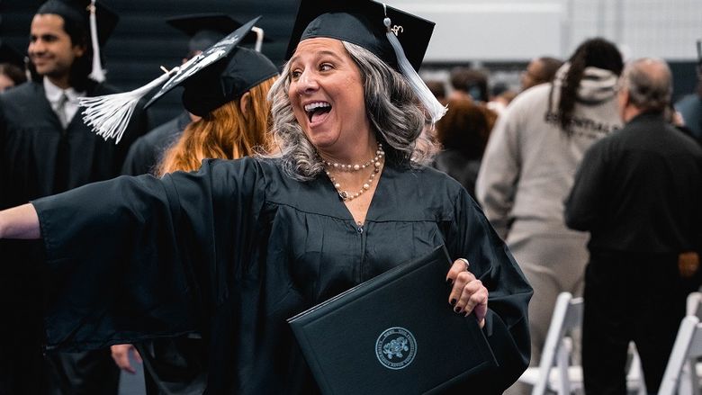 Graduate points and smiles holding diploma