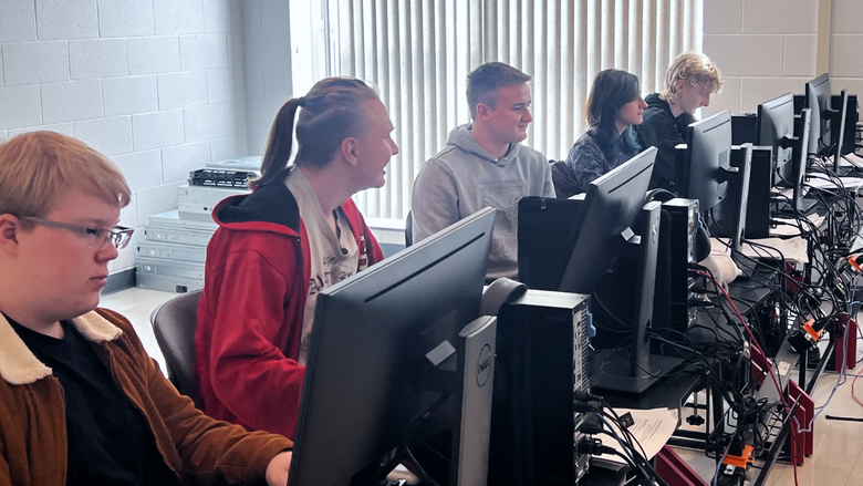 Five students sitting at computers in a computer lab
