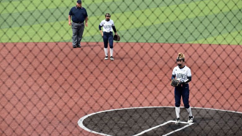 Softball pitcher with a shortstop and umpire in the background