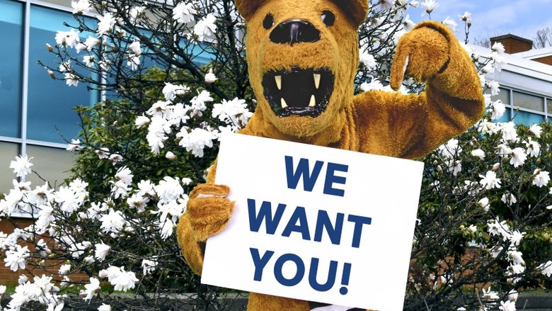 Nittany Lion mascot holding a sign that says "We want you!"