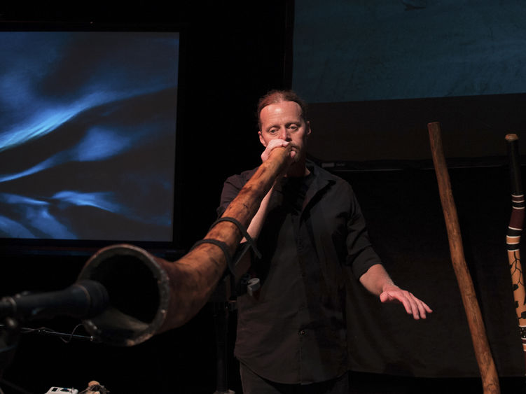 A person playing a didgeridoo into a microphone