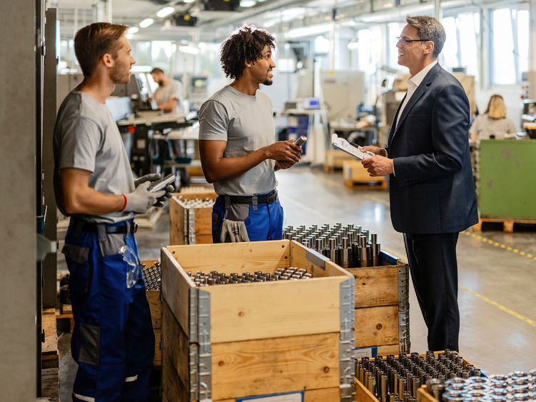 A supervisor discusses production with other employees on the manufacturing floor.