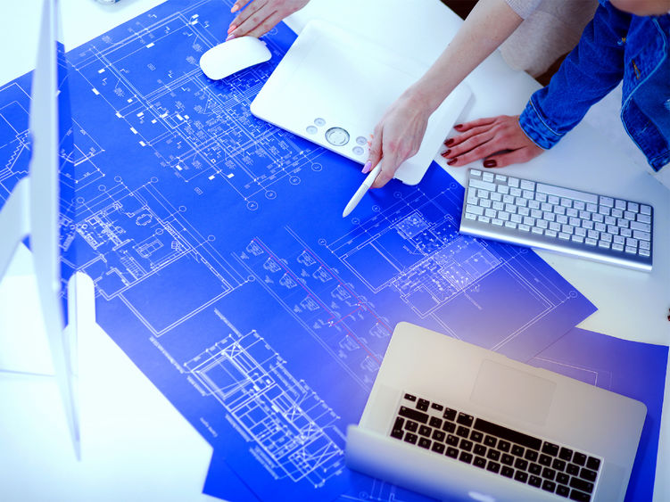 Two individuals reading and marking up a blueprint drawing