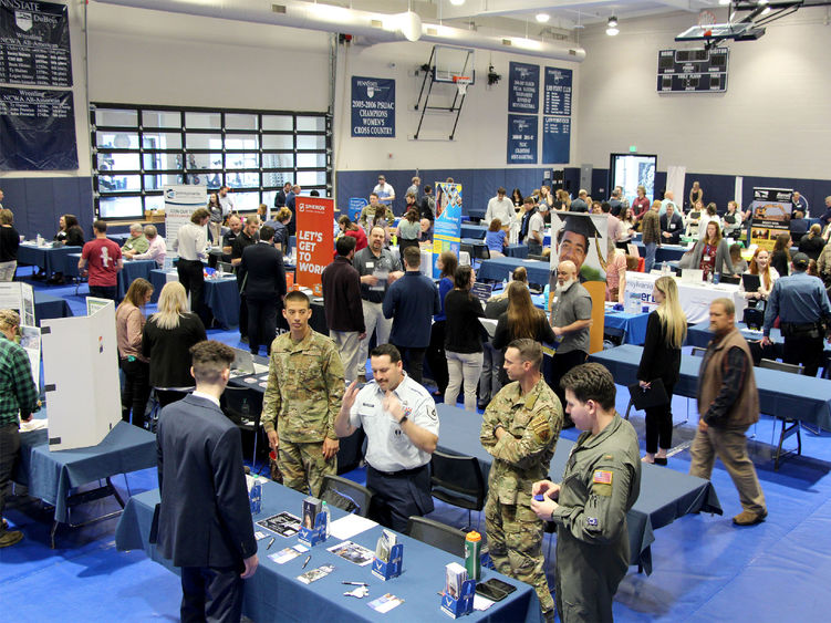 A full gym floor at the PAW Center, with the floor being full of employers, students, alumni and community members during the career fair.