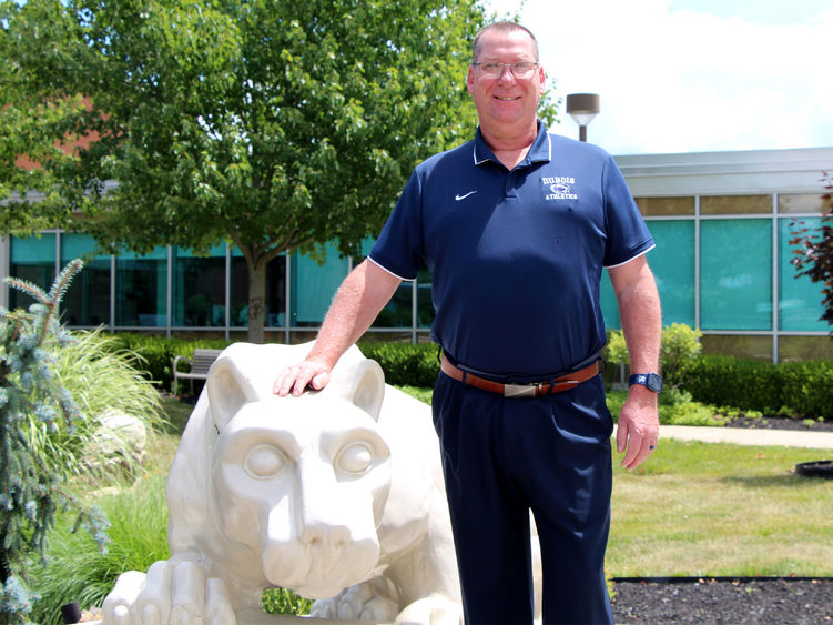 New head golf coach at Penn State DuBois John Schneider stands with the Lion Shrine on campus.