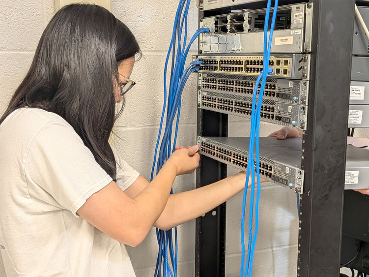 Penn State DuBois student Katy Fritz works on wiring and connecting one of the new Juniper switches that the campus received as part of the new partnership with Penn State IT.