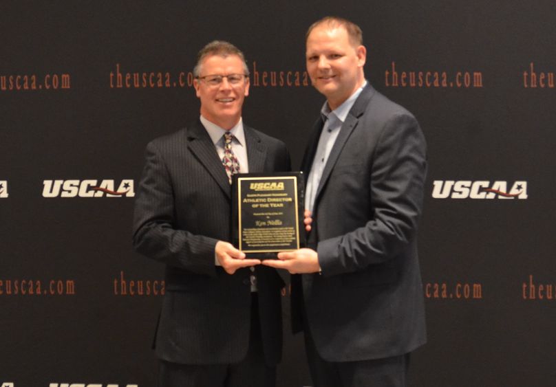 Ken Nellis accepts his Athletic Director of the Year Award from Michael Fischer, president of the USCAA.   