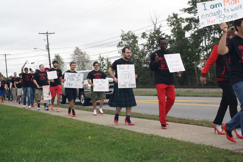 Men in high heels walk along Route 255 near campus during the Walk a Mile in Her Shoes event. 