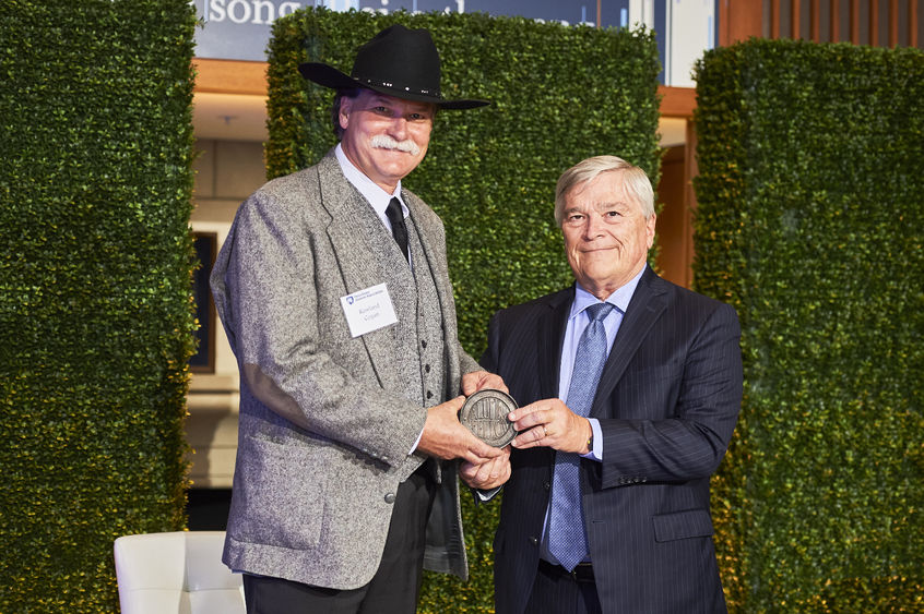 Rawland Cogan accepts his Alumni Fellow award from Penn State President Eric Barron.  