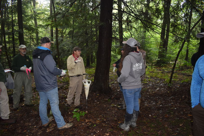 DCNR Forester Bill Laubscher, center, demonstrates the application of insecticide around the base of hemlock trees. 