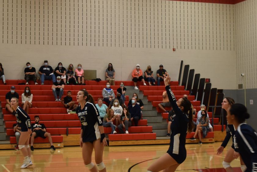 Volleyball players on court during a home match. 