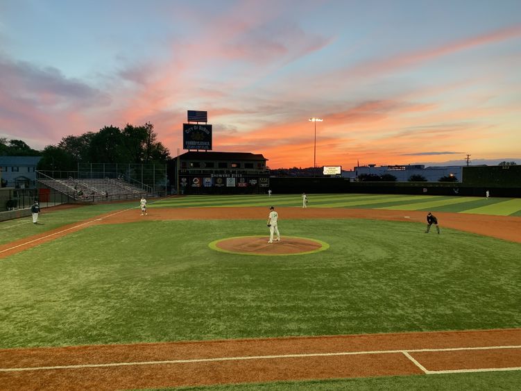 Baseball players at Shower's Field with a sunset.