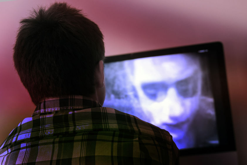 Image of the back of a viewers head while he watches a black and white zombie movie